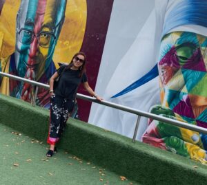 Grace standing in front of the multicultural mural by artist Kobra